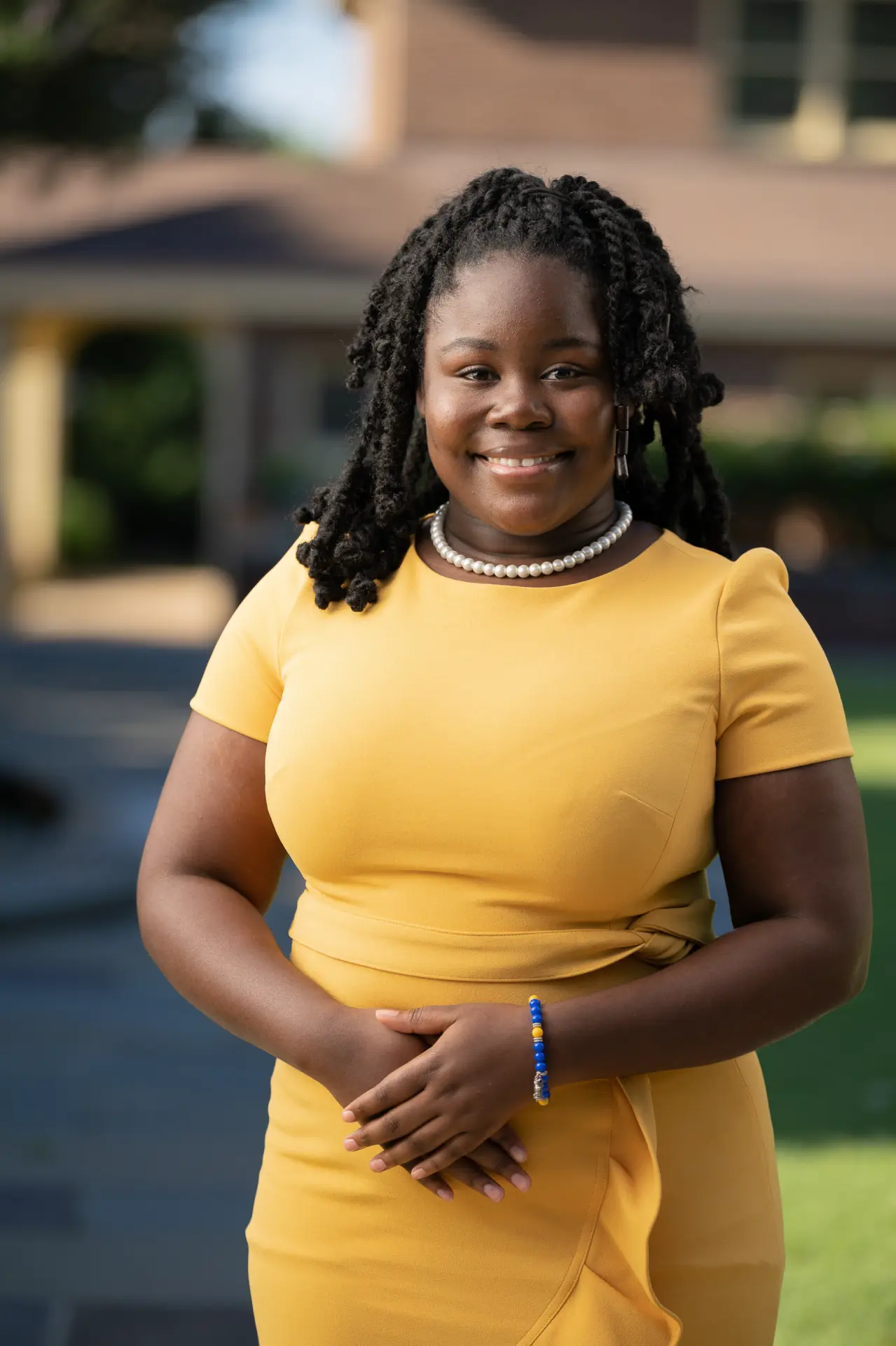 Smiling woman in a yellow dress on a sunny lawn