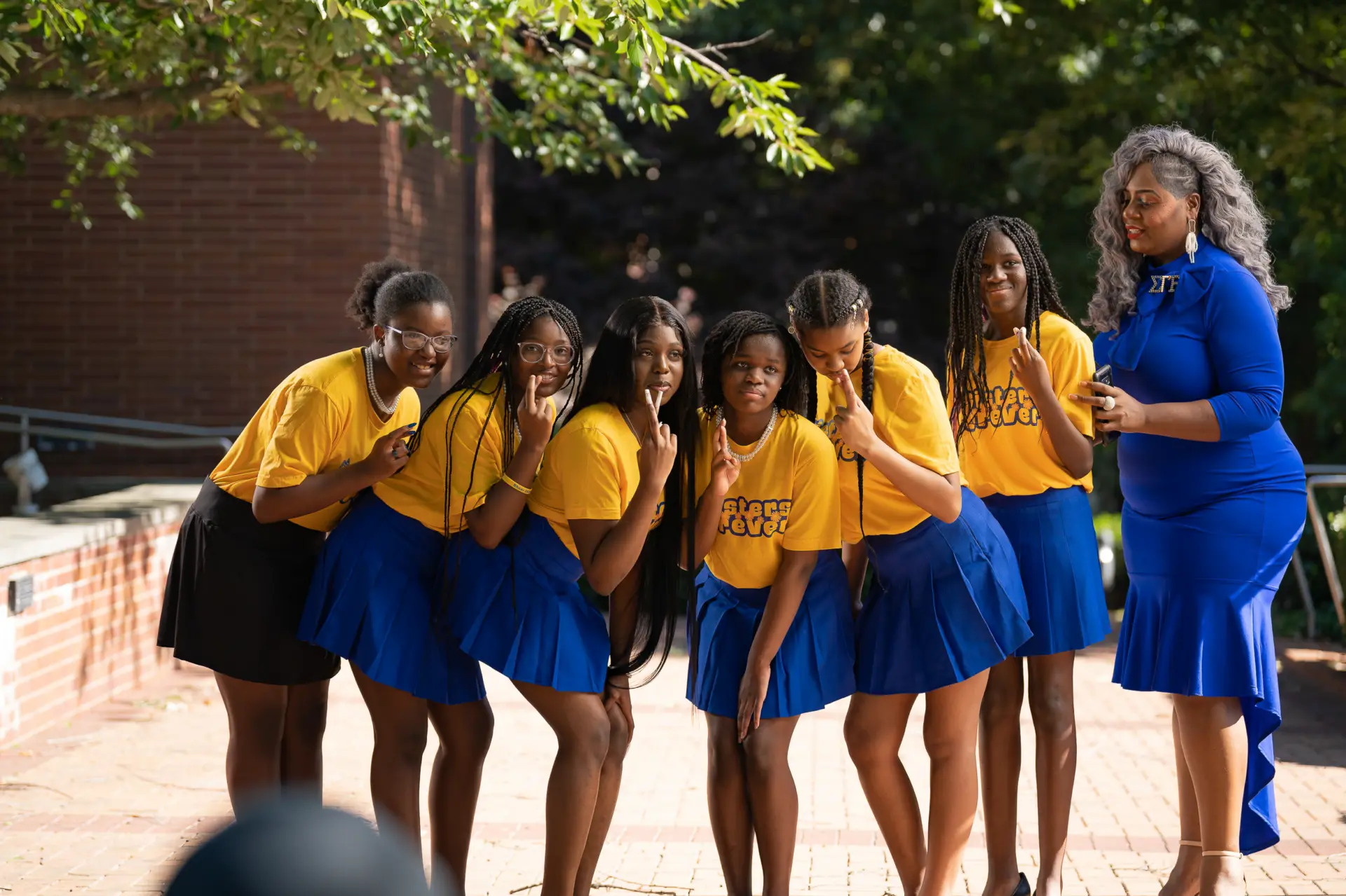 Group photo of members in gold and royal blue outfits outdoors