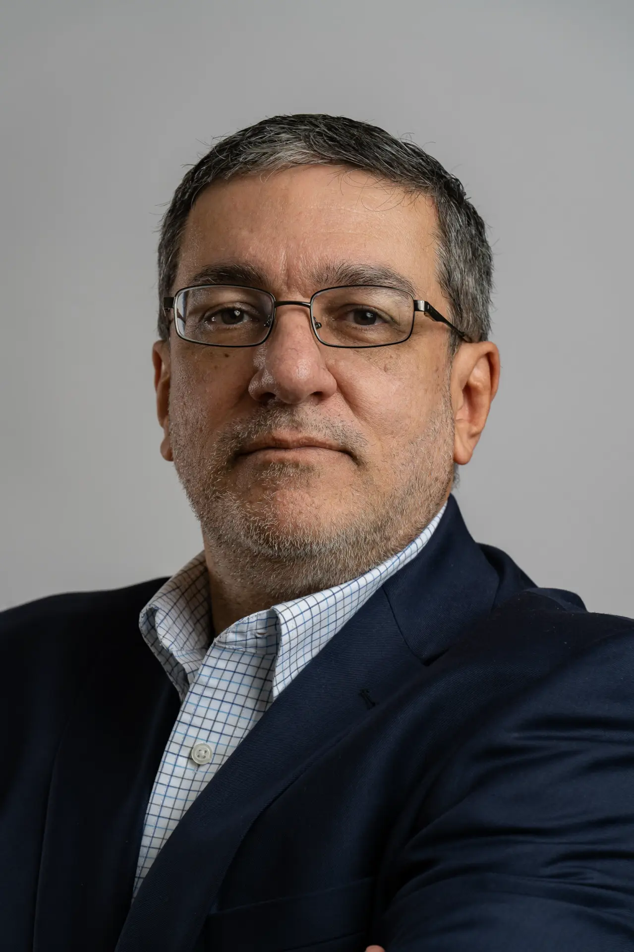 Man with glasses in a dark suit, professional headshot on gray