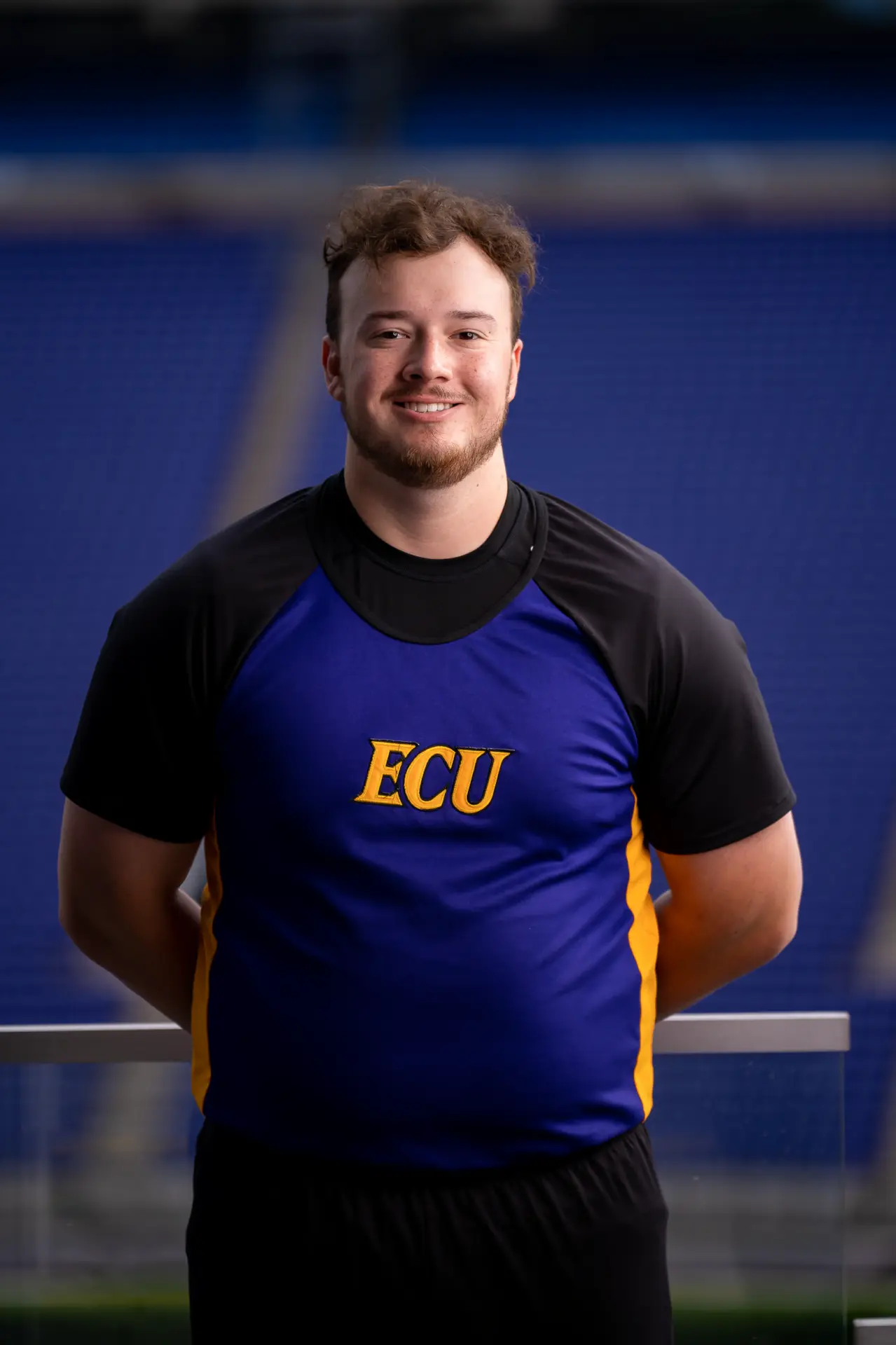 Smiling male ECU cheerleader, team headshot in the stadium
