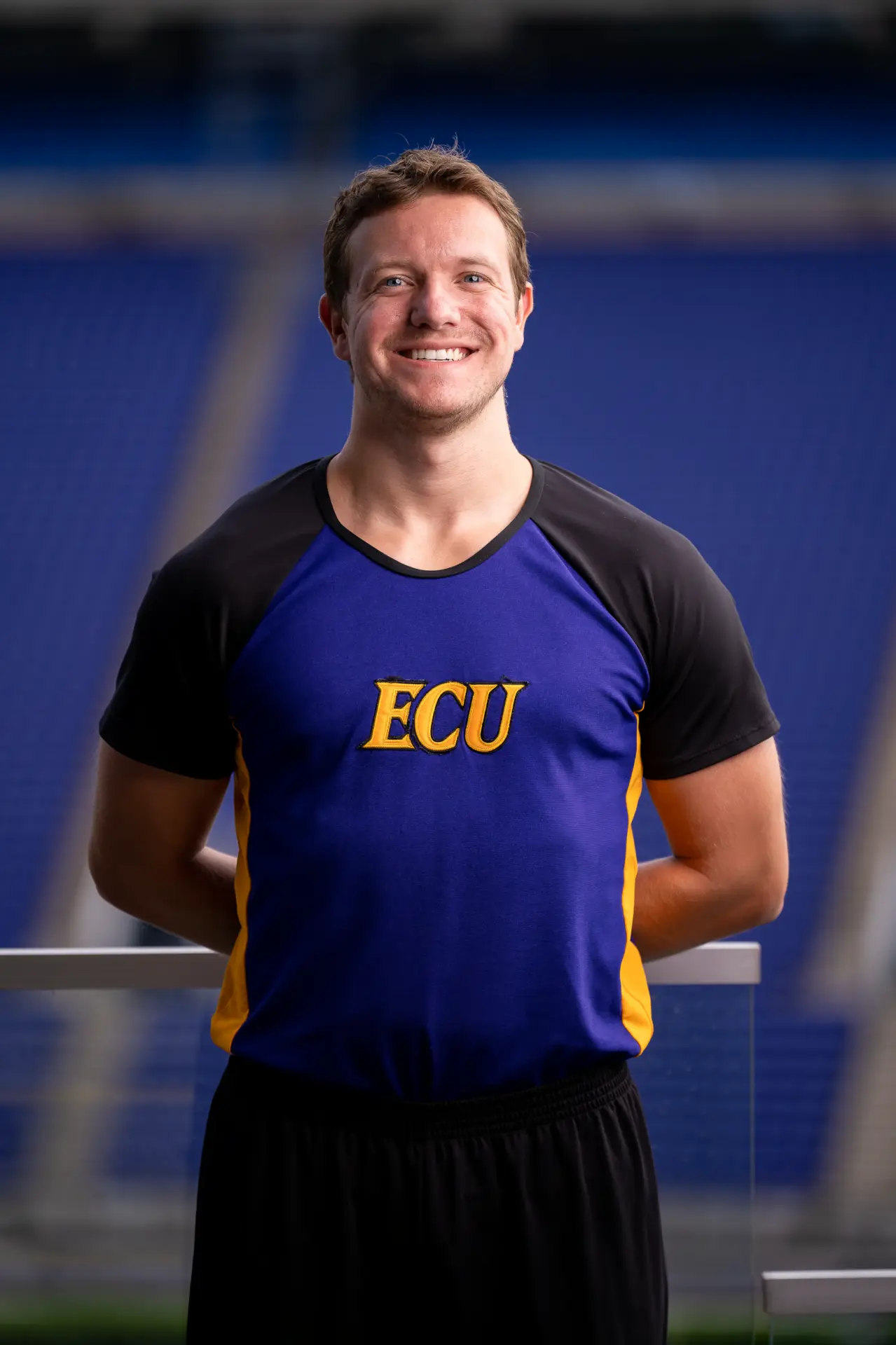 Male ECU cheer team member posing on the field