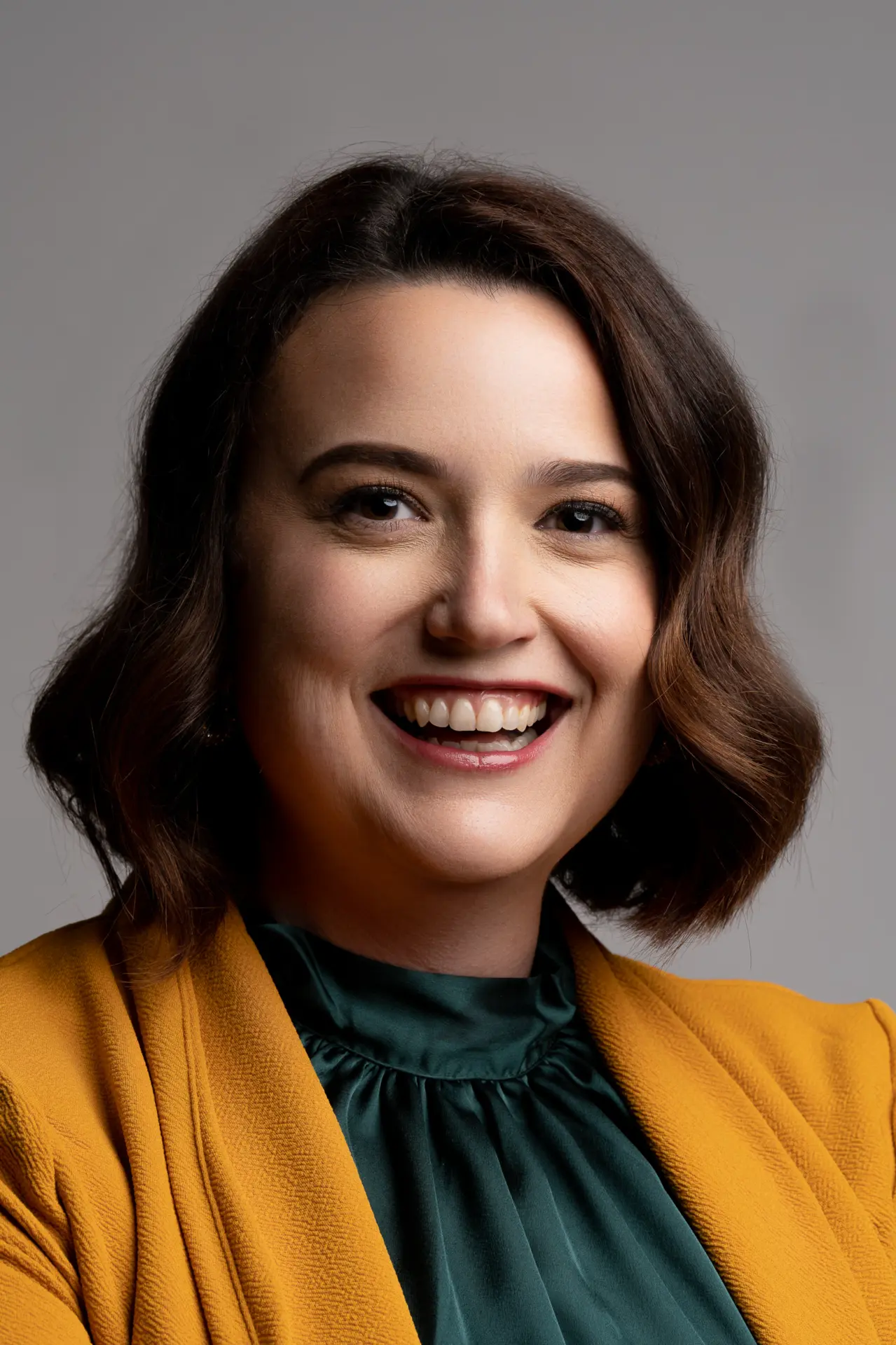Woman in a mustard cardigan smiling, warm professional headshot