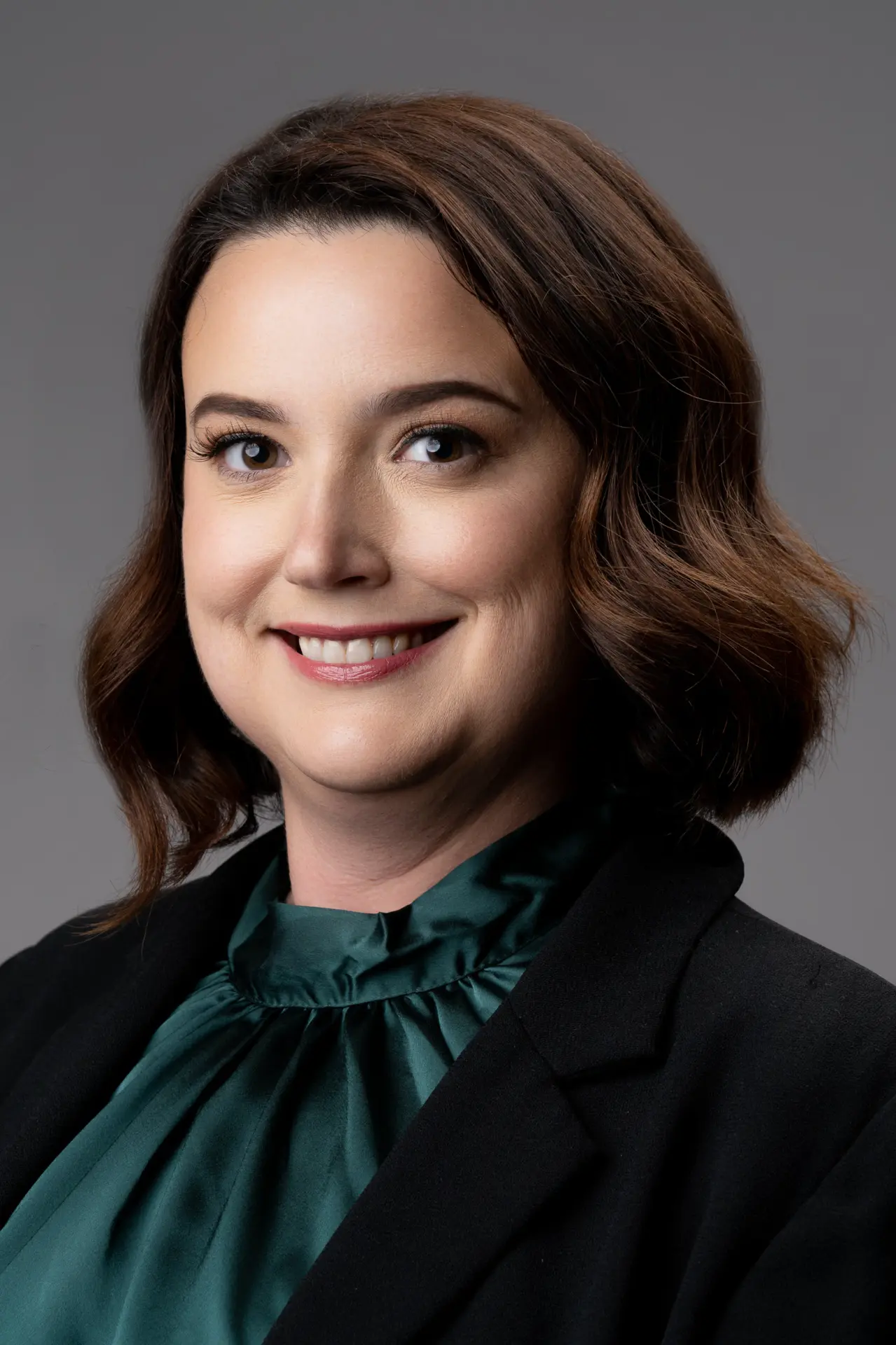 Smiling woman with a bob in a green blouse, studio headshot