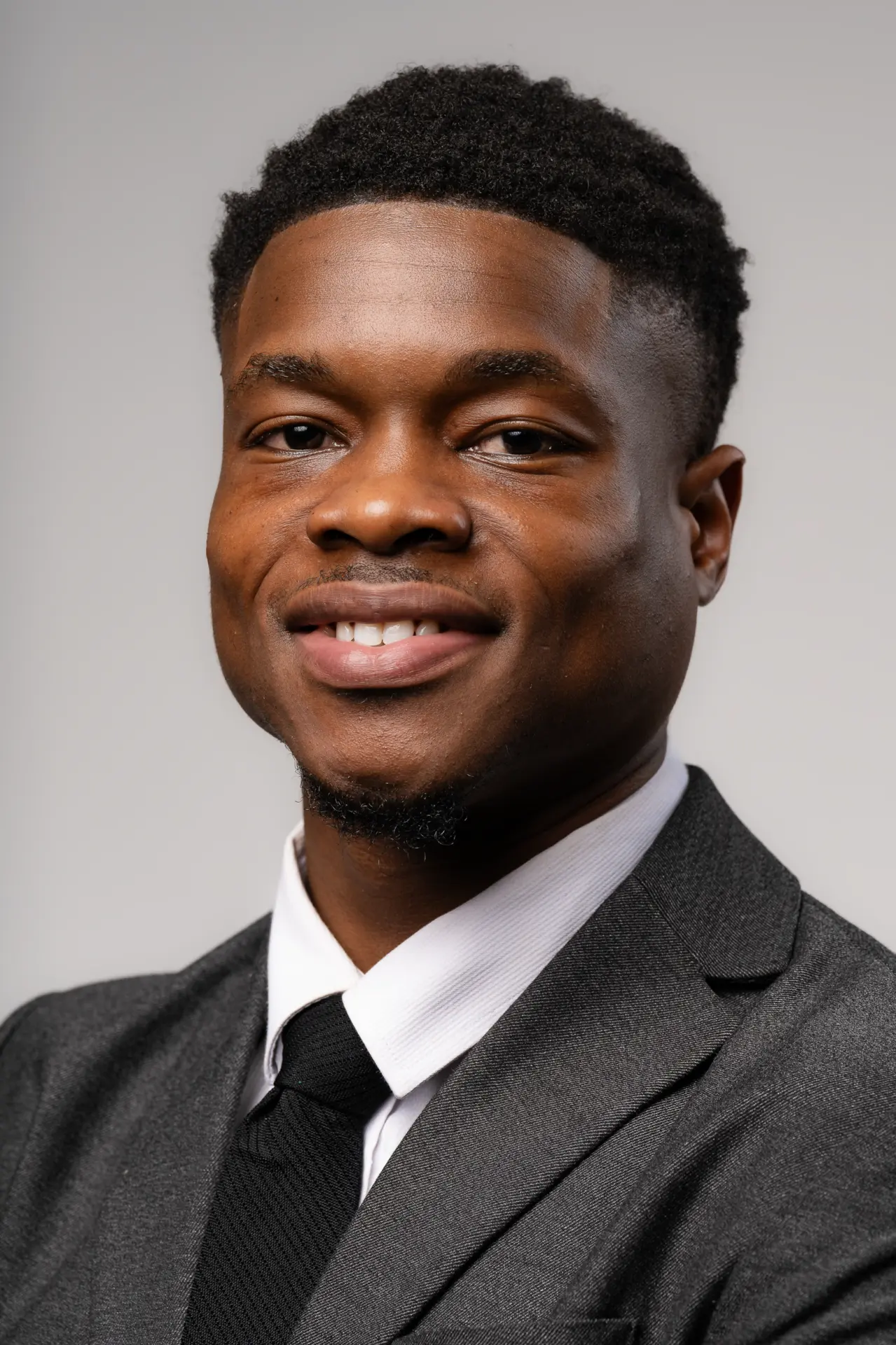 Smiling young man in a gray suit and tie, studio headshot