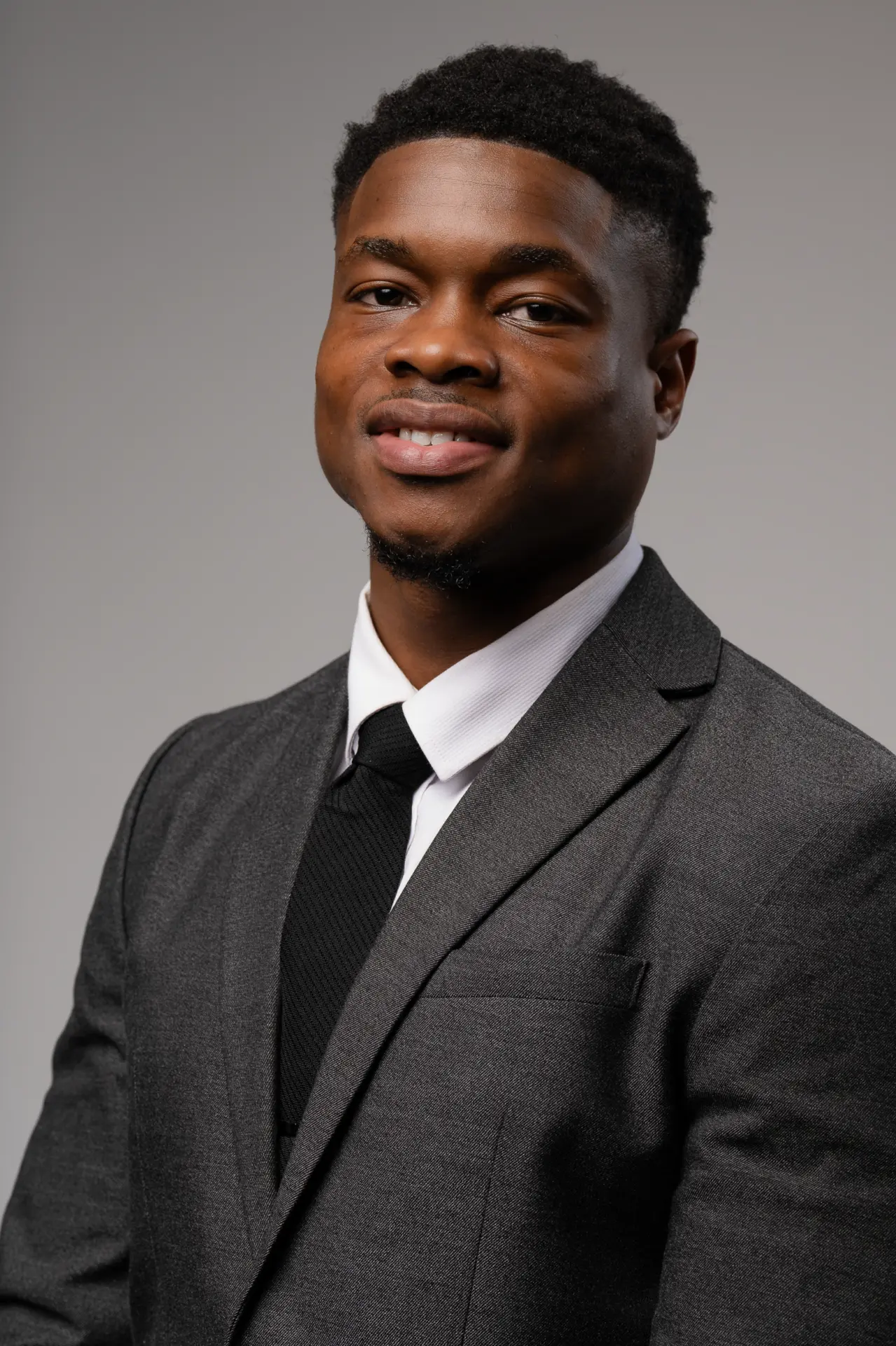 Young man in a charcoal suit, professional headshot on gray