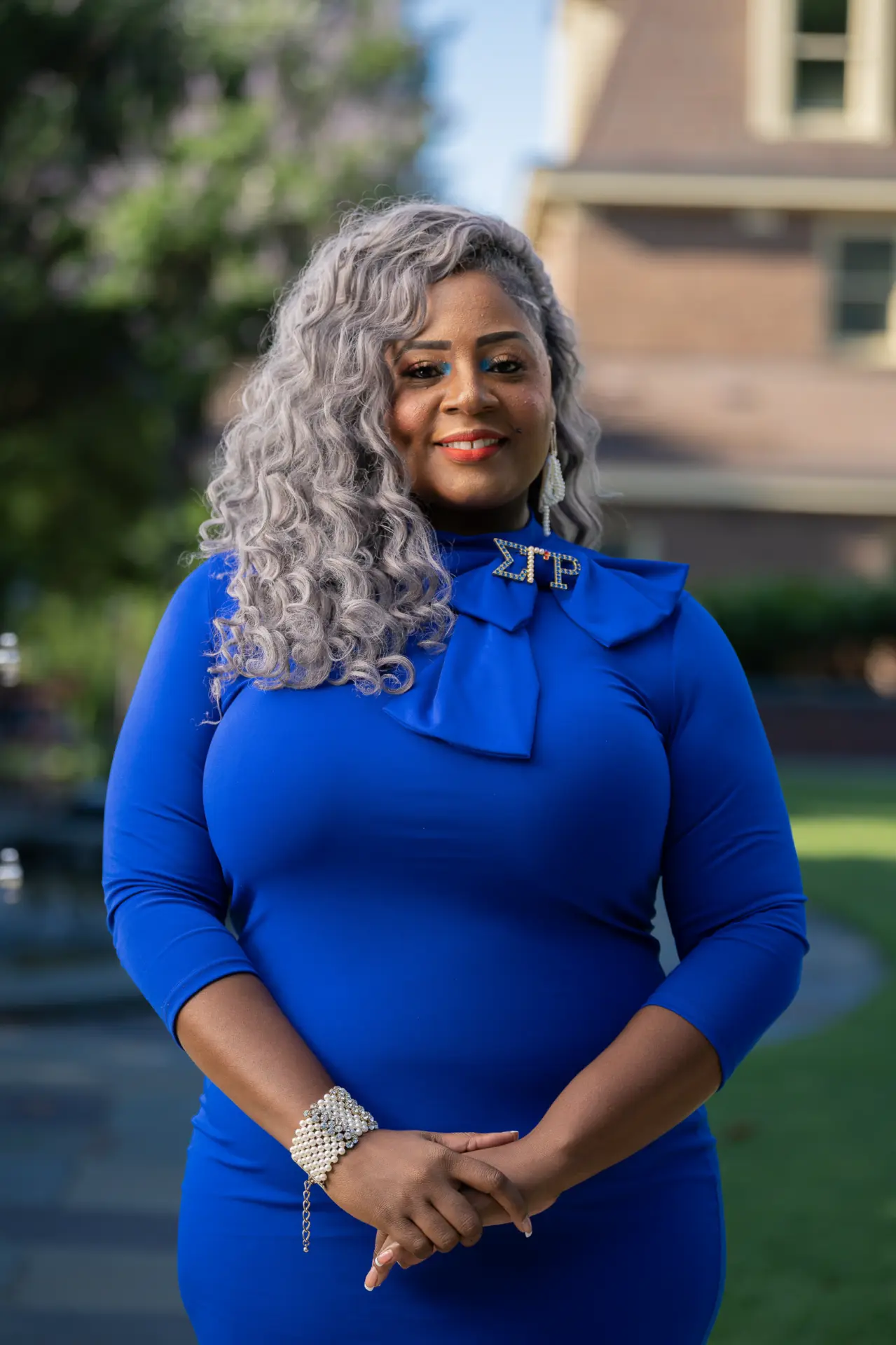 Woman with silver curls in a royal blue dress outdoors