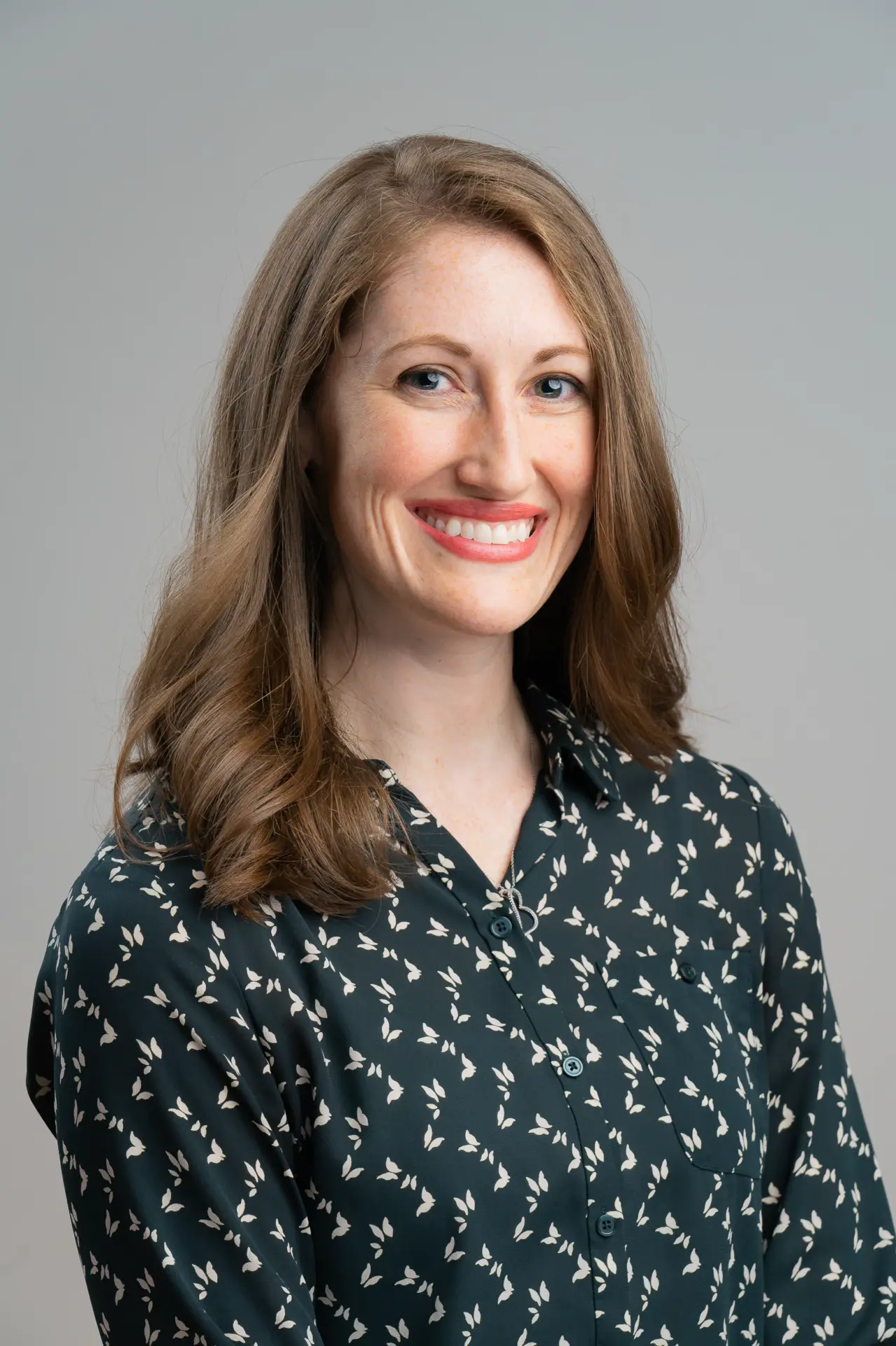 Smiling woman in a patterned green blouse, professional headshot