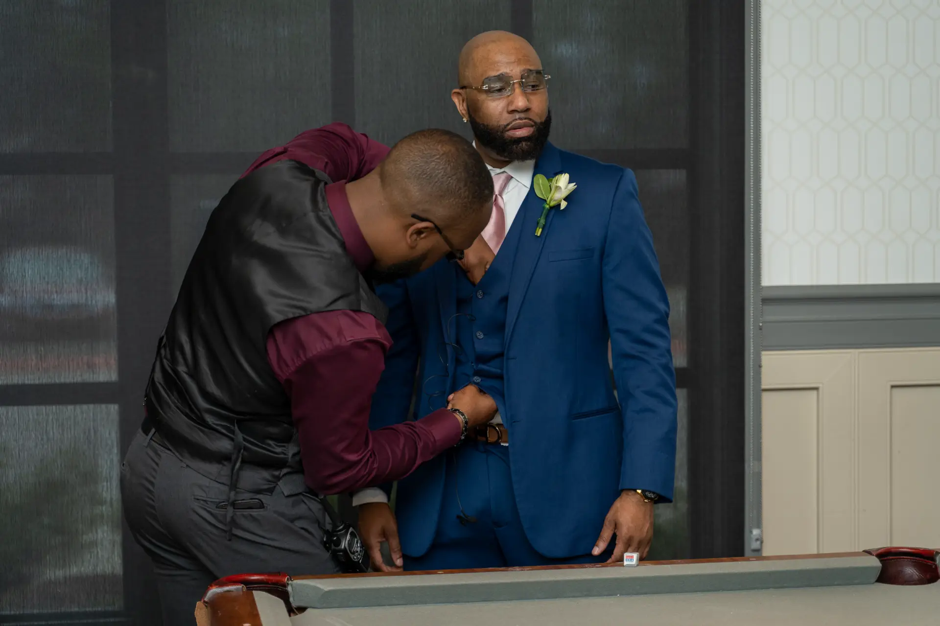 Groom in a blue suit embraces a groomsman before the ceremony