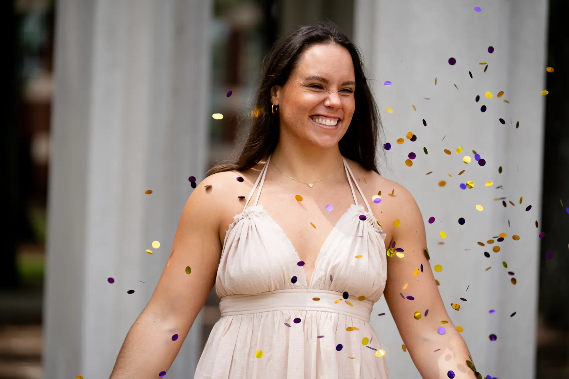 Graduate in a sparkly dress tossing confetti