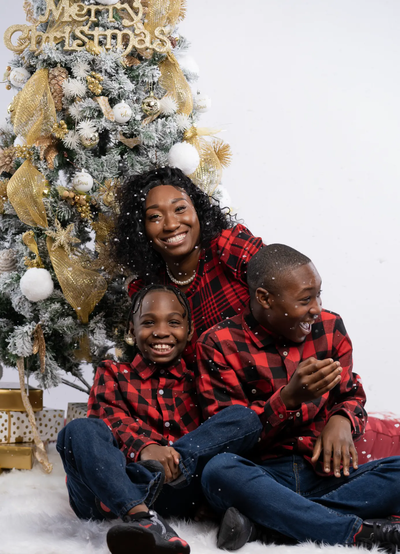 Family in matching red plaid pajamas beside a Christmas tree