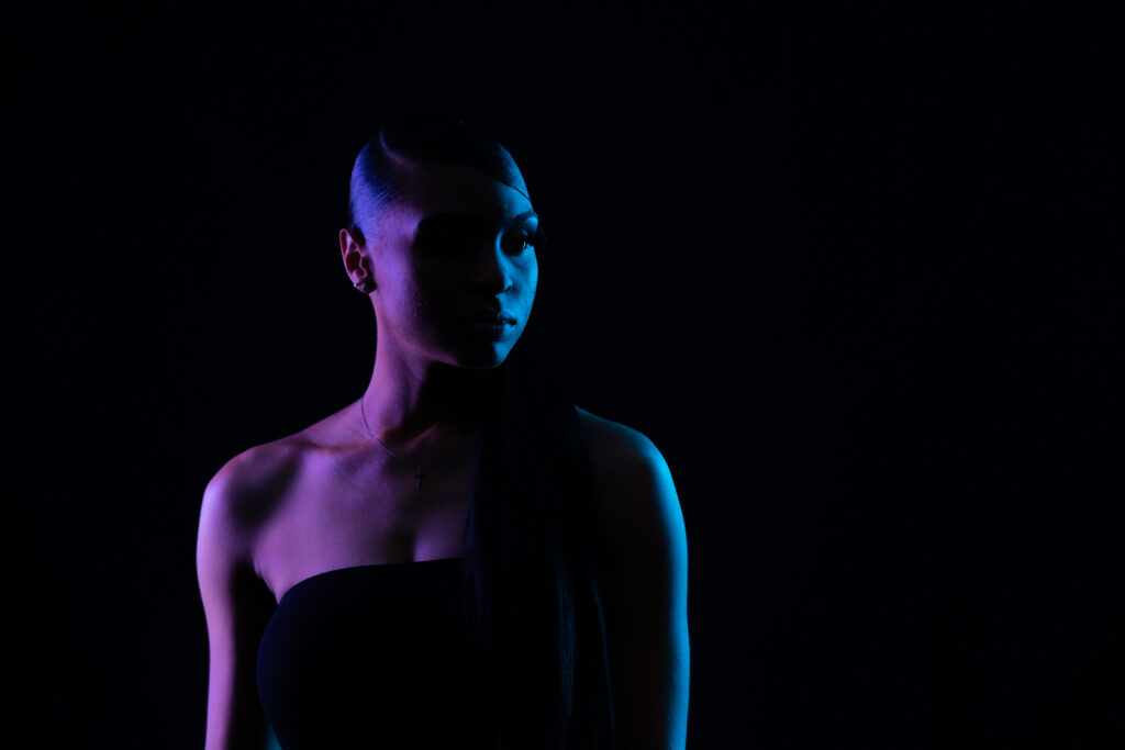 Woman in profile with colored gel lighting on black