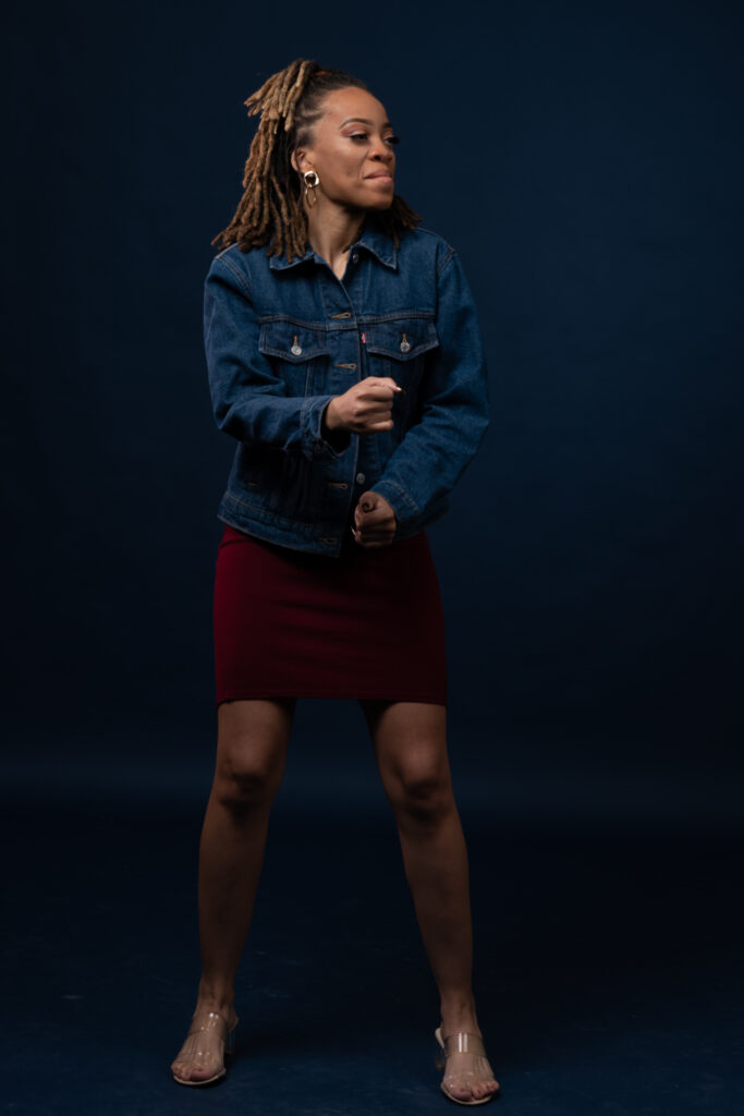 Woman in a denim jacket and red skirt on a deep blue backdrop