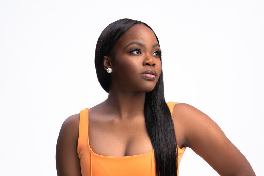 Woman in an orange top gazing upward, bright studio portrait