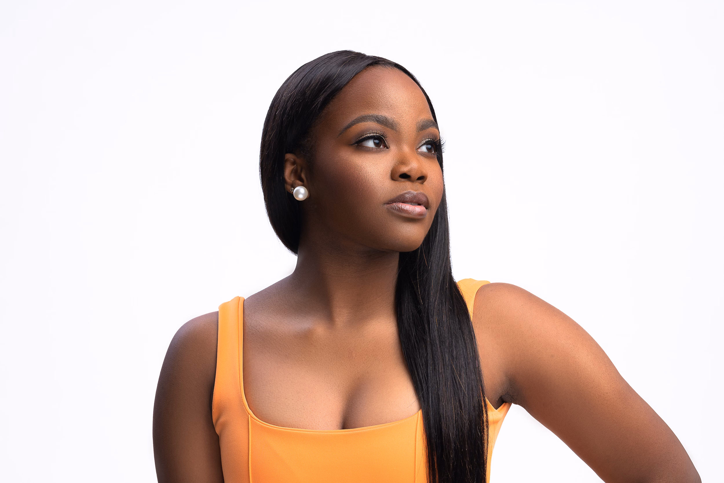 Woman in an orange tank top looking over her shoulder on white