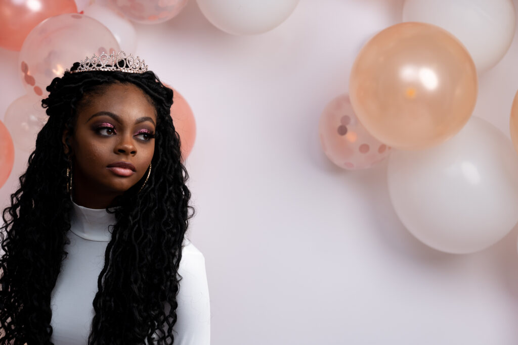 Woman with long braids beside peach balloons