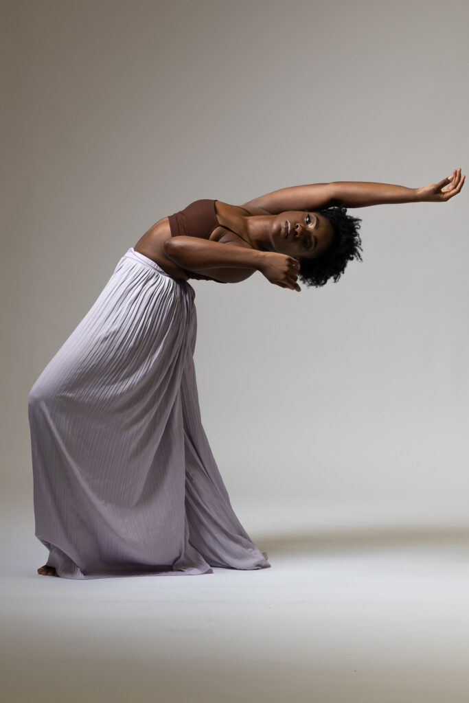 Dancer arching backward in a flowing gray skirt