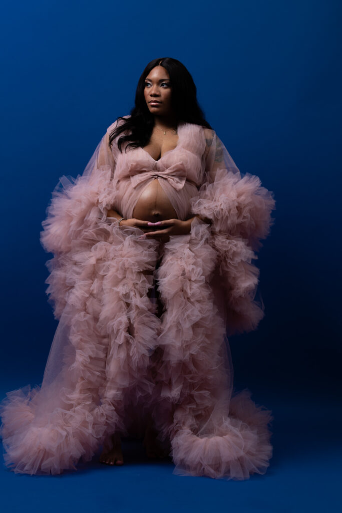 Woman in a sheer pink tulle robe on a royal blue backdrop