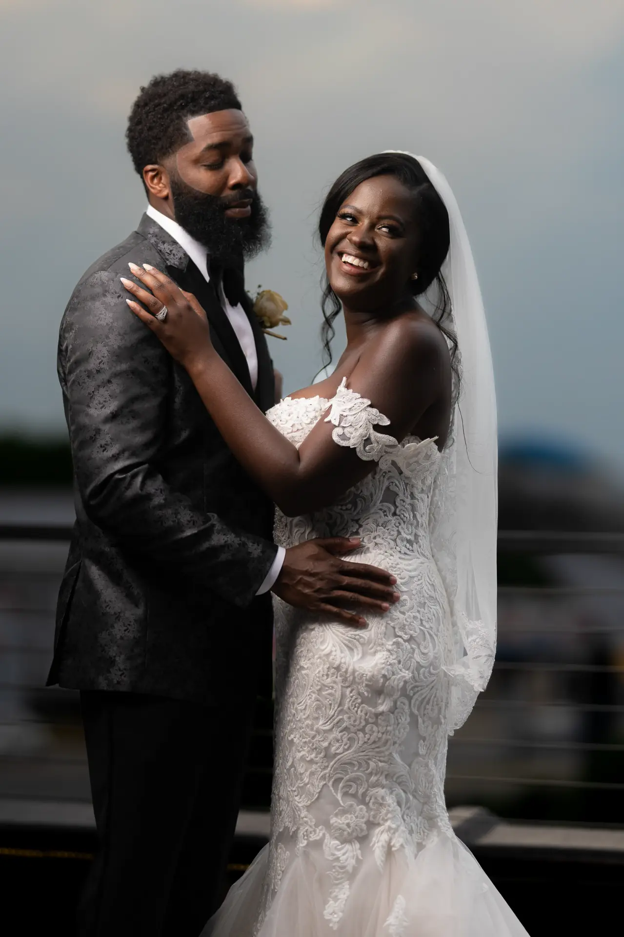 Groom holds the bride close as she smiles at the camera