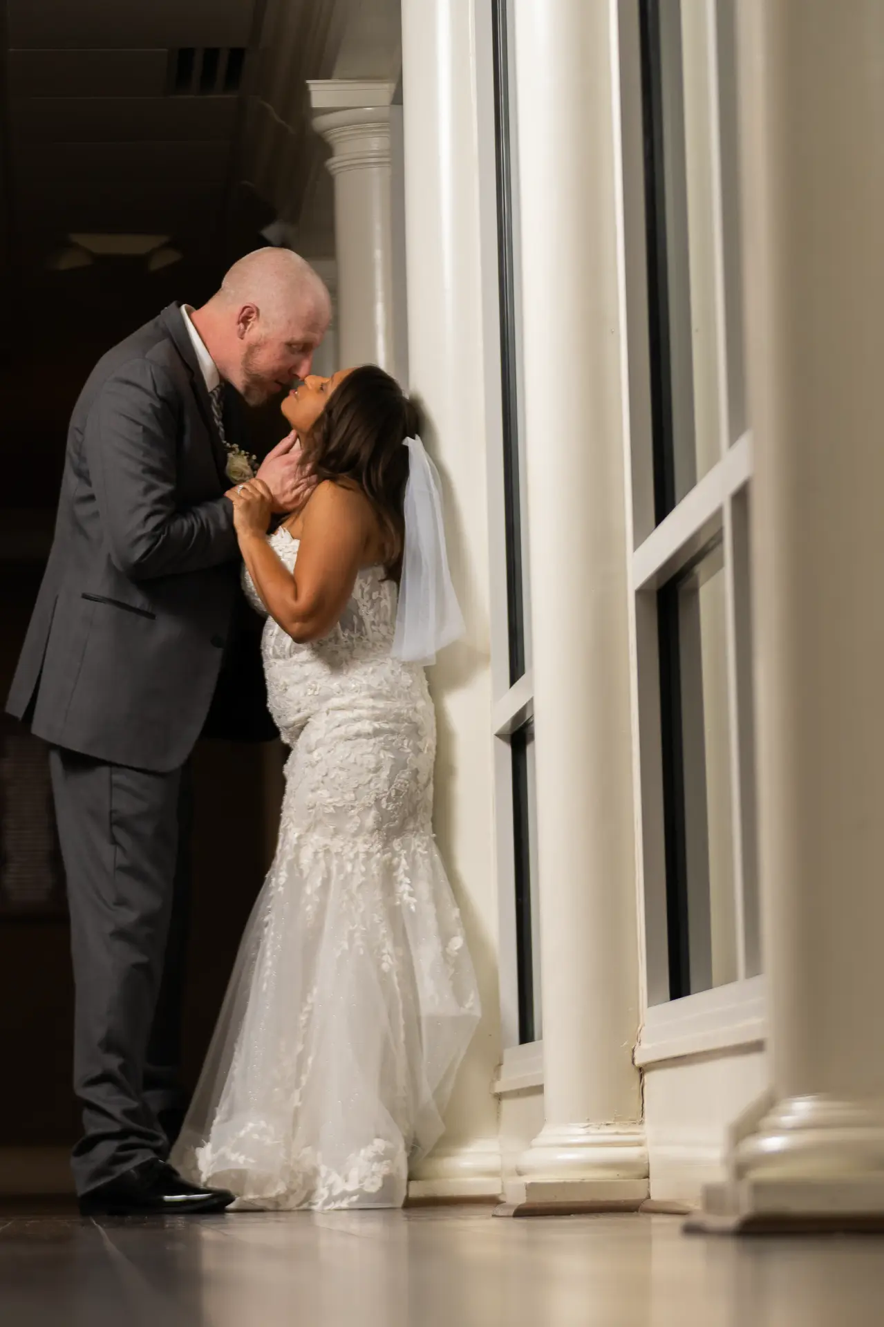 Bride and groom kiss beside tall white columns