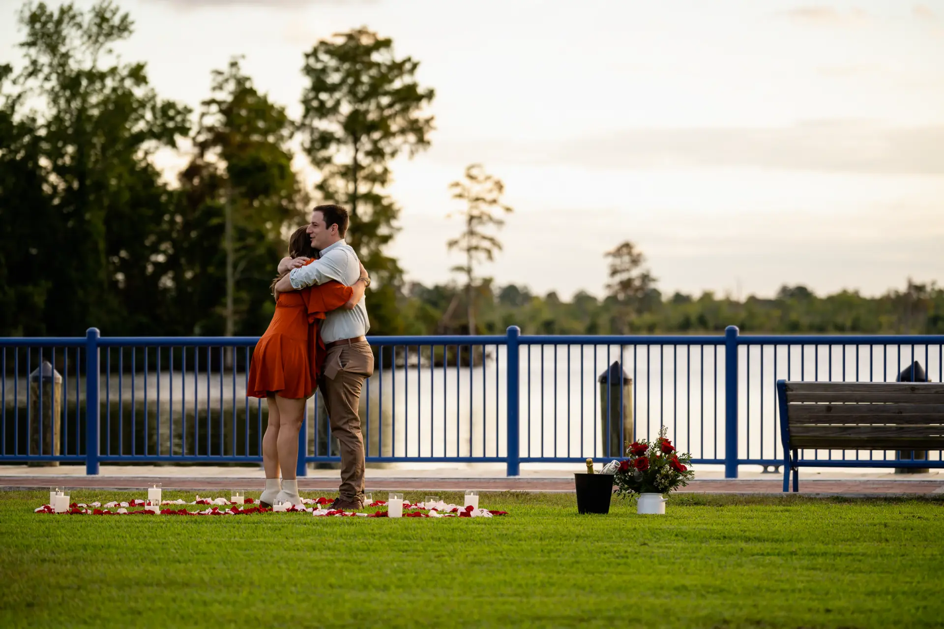 Proposal setup by the lake with a couple embracing on the lawn
