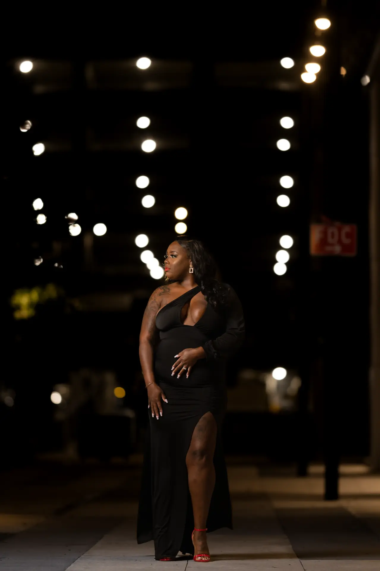 Bride in a fitted gown stands in a dark reception hall