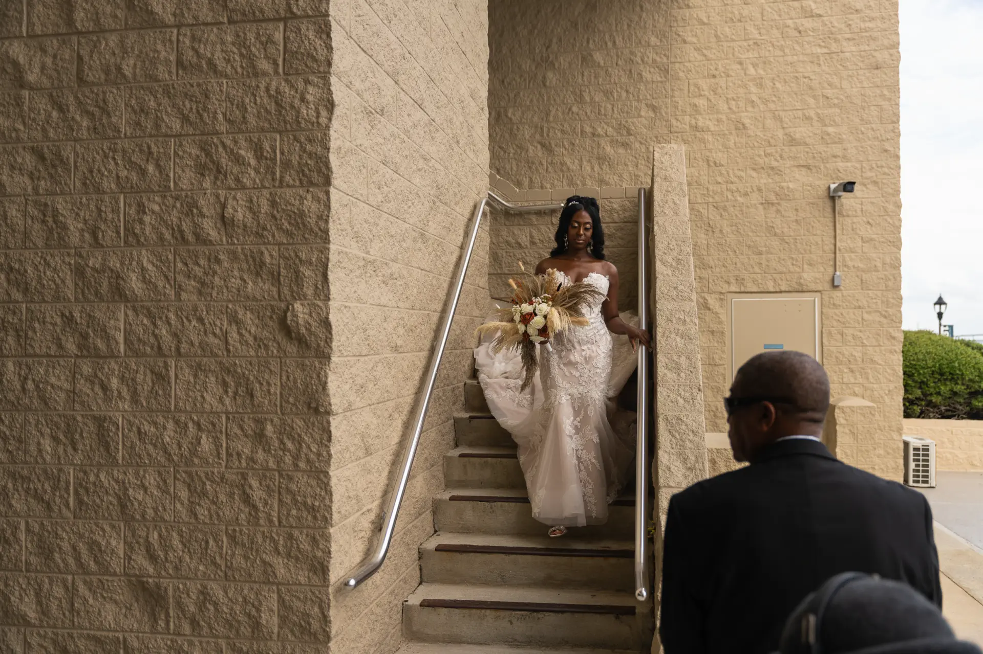Bride walks down a stairwell toward the waiting groom