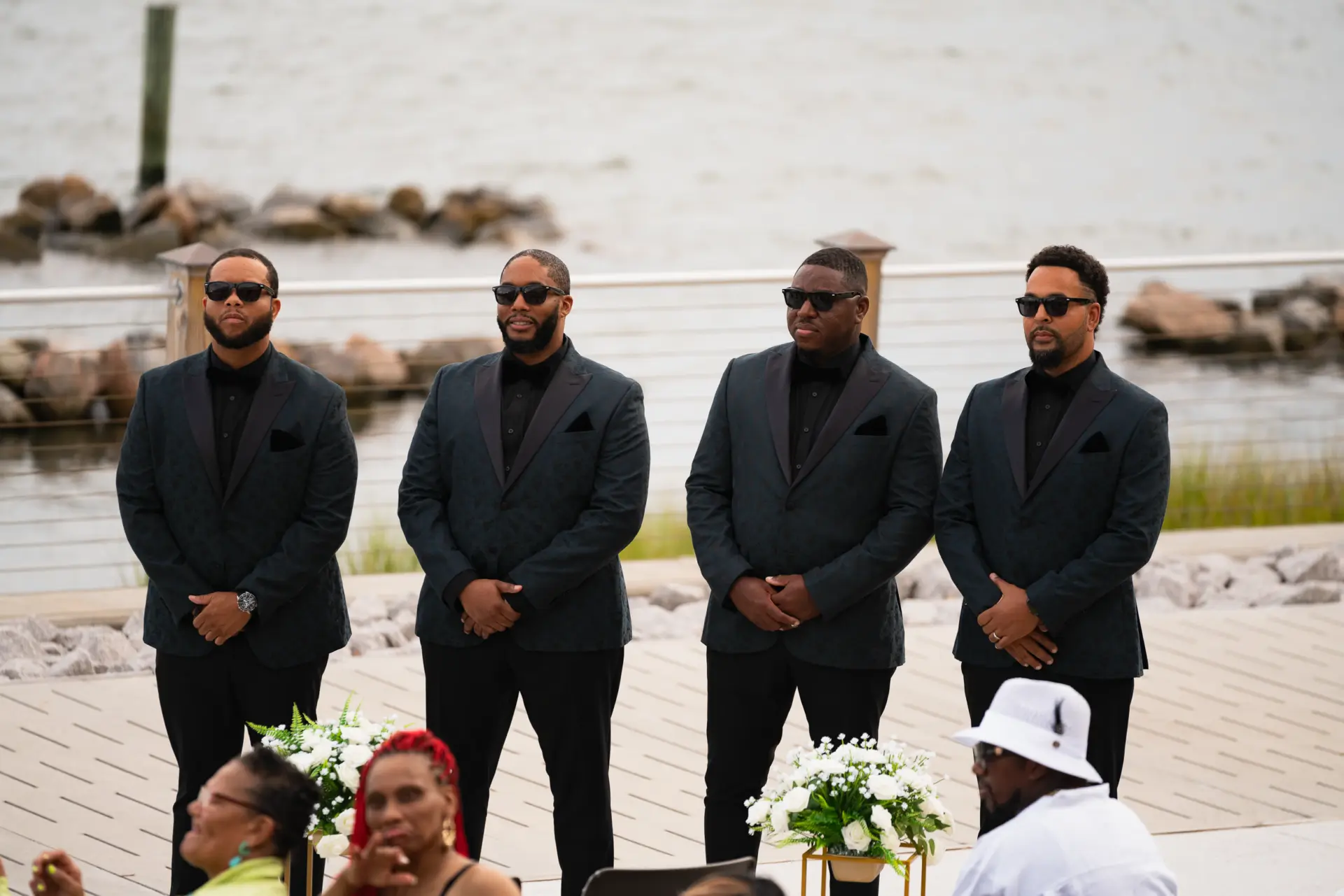Groomsmen stand together at a waterfront ceremony