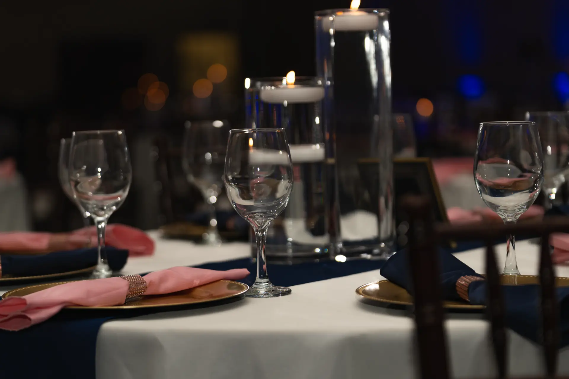 Reception table set with stemware and candlelight under blue uplighting